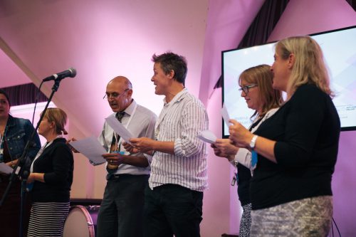 A group of music teachers sing at an expo event