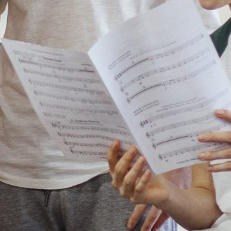 A close up image of a young persons hand holding sheet music