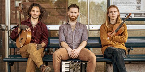 Members of the band Tarren sit on a bench holding their musical instruments